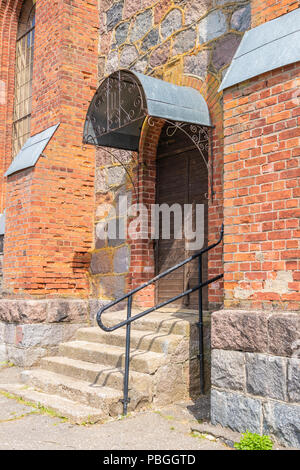 Alte hölzerne Tor mit einem Bogen in der Wand aus Ziegel und Stein Stockfoto