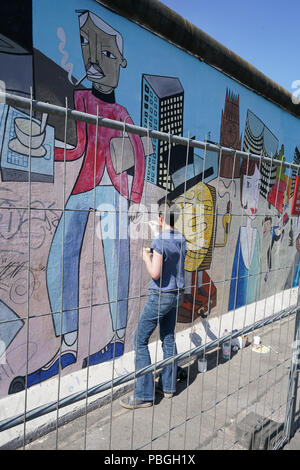 Künstler bei der Beseitigung von Graffiti an der East-Side Gallery in Berlin. Stockfoto