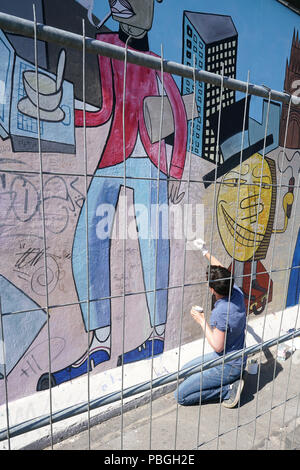 Künstler bei der Beseitigung von Graffiti an der East-Side Gallery in Berlin. Stockfoto