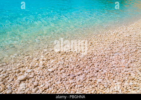 Ein Kiesstrand mit türkisfarbenem Wasser. Sommerferien Konzept. Stockfoto