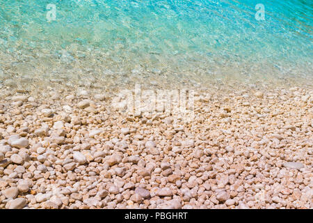 Ein Kiesstrand mit türkisfarbenem Wasser. Sommerferien Konzept. Stockfoto