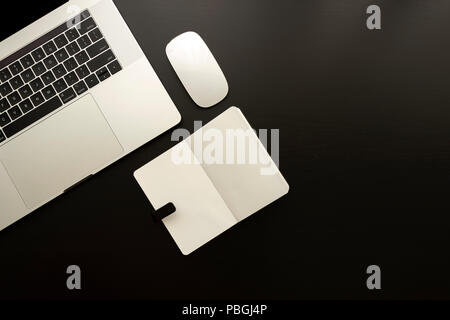 Skizzenbuch Laptop und bewegen Sie die Maus über die schwarzen Holztisch monochromatischen Flachbild Komposition legen Stockfoto