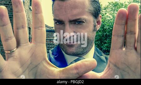 Closeup Portrait von einem gutaussehenden Mann in einem smart Anzug seine Hände hielten vor der Kamera Stockfoto