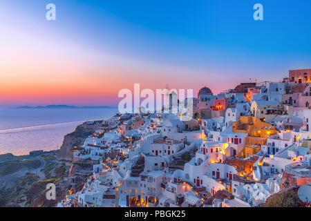 Atemberaubende Aussicht auf das Dorf Oia auf Santorini in der Dämmerung mit bunten Twilight und weißen Häusern, Windmühle auf der Klippe, Griechenland. Stockfoto