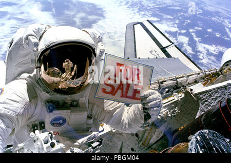 Astronaut Dale A. Gardner, der gerade den größten Teil seines zweiten Extra Vehicular Activity (EVA) Zeitraum in drei Tagen, hält ein Schild "Zum Verkauf" bezieht sich auf die beiden Satelliten, Stockfoto