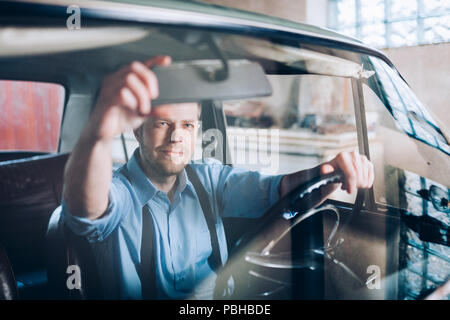 Schöner Mann in seinem alten Oldtimer sitzen Stockfoto
