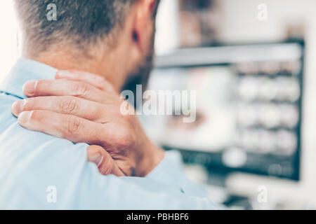 Büroangestellter mit Nacken- und Rückenschmerzen vom sitzen den ganzen Tag am Schreibtisch Stockfoto