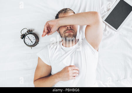Müde Mann schlafend auf dem Bett nach der Verwendung seiner digitalen Tablet Stockfoto