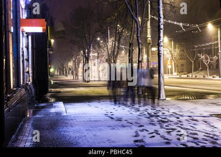 Verschwommene oder Defokussierten Bild der Gesellschaft von Menschen zu Fuß entlang der schneebedeckten Straße in der Nacht Stadt Stockfoto