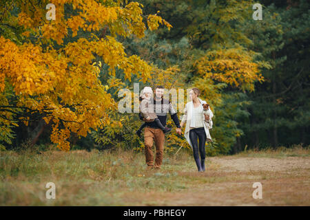 Junge Eltern mit ihrer Tochter halten Sie Hände und am Waldweg mit Hund beim Spaziergang im Wald. Stockfoto