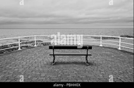 Ein Badeort, der Sitzbank mit Blick auf das Meer an einem bewölkten Tag in Aberystwyth Wales Stockfoto