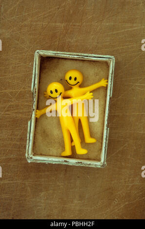 Zwei gelben Kunststoff smiley bendy Männer mit offenen Armen und umarmen Stockfoto