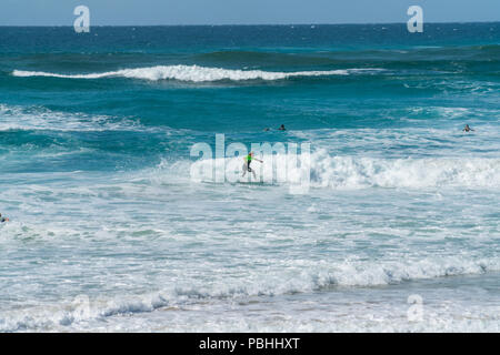 COOLANGATTA, AUSTRALIEN - 10 Juli 2018; Breite Surf Beach mit Surfer reiten durch White Wave Schaum mit Tief türkisblauen Meer hinter Stockfoto