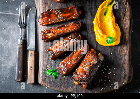 Lecker gebratene Rippen mit Gemüse und Kartoffel auf dunklen Tabelle Stockfoto