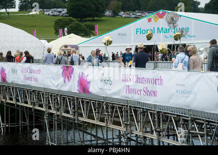 Die Menschen Kommen & Gehen an belebten RHS Chatsworth Flower Show, einige Wandern & Kreuzung temporäre River Bridge von großen festzelten - Derbyshire, England, UK. Stockfoto