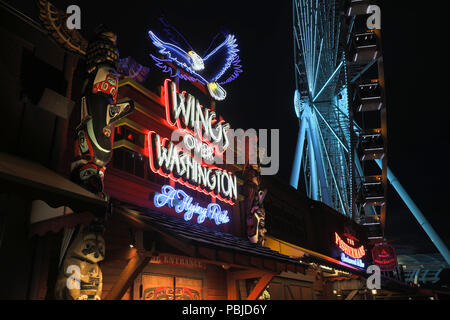 Seattle, Washington - 30. Juni 2018: Pier 57 in der Nacht mit leuchtreklamen von touristischen Unternehmen und der großen Riesenrad in Seattle, WA. Seattle's Wasser Stockfoto