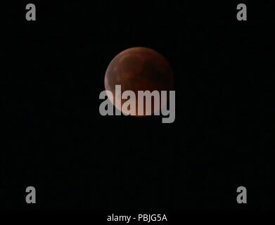 Berlin, Deutschland. 27. Juli, 2018. Für eine Stunde und 43 Minuten, der Mond ist völlig in den Schatten der Erde versenkt. Der Mond erscheint dann als rötliche Scheibe am Himmel. Das Foto zeigt den Mond über dem Brandenburger Tor. Quelle: Simone Kuhlmey/Pacific Press/Alamy leben Nachrichten Stockfoto