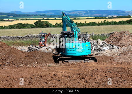 Große gegen Kleine in den Anlagen, Maschinen, zwei Bagger bei der Arbeit in einem Feld wiederhergestellt wird nach Abschluss der Bauarbeiten zu Ackerland. Stockfoto