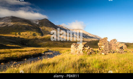 Ein gebirgsbach fließt aus den Hängen des Beinn Eighe Berge und vorbei an den Ruinen eines kleinen Gebäudes im Glen Torridon in den Torridon Hills bereich t Stockfoto