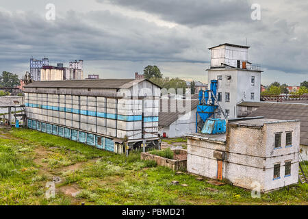 Vitebsk, Belarus - Juli 7, 2018: industrielle Landschaft: mehrere alte Ziegel lagern und Maschine für Sichten Korn in Wetter. Stockfoto