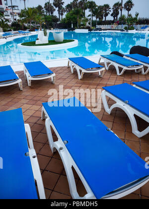 Sonnenliegen am Pool bei Nacht/Dämmerung auf Teneriffa. Eine Reihe von leeren Sonnenliegen zum Sonnenbaden und am Rand des Swimming Pool auszuruhen. Stockfoto