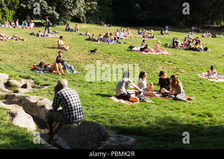 Paris Park - Leute genießen heißen Nachmittag im Parc des Buttes Chaumont in Paris, Frankreich, Europa. Stockfoto