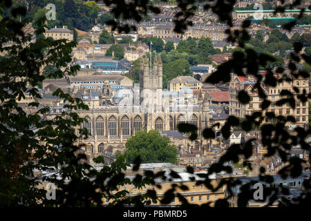 Bath Abbey durch Bäume von einem hohen Aussichtspunkt über die Stadt Bath in England gesehen Stockfoto