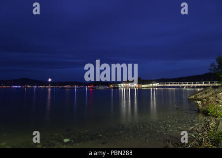 COEUR D'Alene, Idaho, USA - Juli 4, 2018: Die zedern schwimmenden Restaurant am Lake Coeur d'Alene bei Dämmerung mit Booten und Feuerwerk im Hintergrund Stockfoto