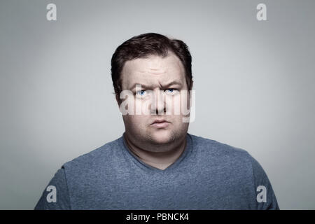 Close-up Portrait von weissen Kaukasischen Big Fat stout Mann mit blauen Augen direkt in die Kamera im Studio auf hellem Grund, skeptisch Verdächtige e Stockfoto