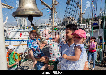 Russland, Wladiwostok, 28.07.2018. Portrait von Happy Family in der Nähe von per Schiff Bell von Segelboot "Pallada". Junge Junge versucht, die Glocke zu läuten. Konzept der mariti Stockfoto