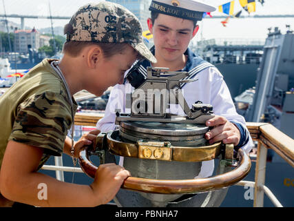 Russland, Wladiwostok, 28.07.2018. Junge schaut in Richtung finder auf dem Deck des Segelboot "Pallada". Seemann in offiziellen Marine uniform hilft Stockfoto