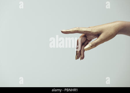 Golden bemalte Hand über grauer Hintergrund zeigt. Weibliche Hand in goldener Farbe zeigenden Finger. Stockfoto