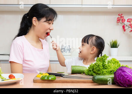 Asiatische chinesische Mutter und Tochter, Salat in der Küche zu Hause. Stockfoto