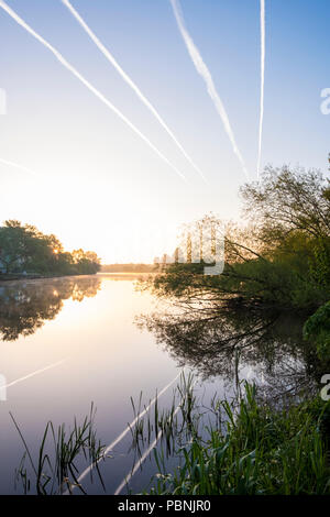 Kondensstreifen am Himmel über dem Fluss Trent und die umliegende Landschaft in der Morgendämmerung, Nottinghamshire, England, Großbritannien Stockfoto