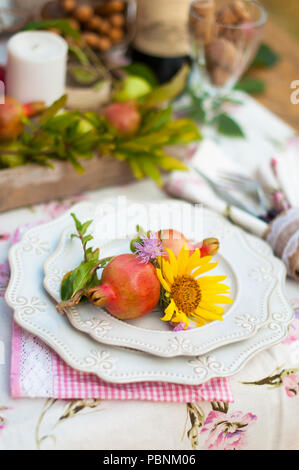 Romantisches Abendessen im Herbst Garten, Einstellung für ein schönes Abendessen. Wein, Obst, Granatapfel und Blumen. Picknick im Freien Stockfoto