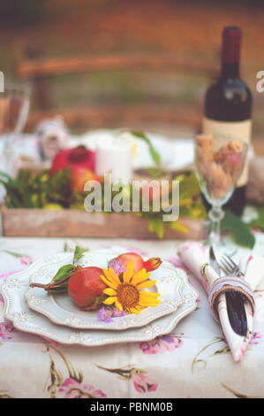 Mittagessen im Garten mit Wein und Obst. Romantisches Abendessen im Freien. Blätter im Herbst Blumen. Schöne Tabelle Scrapbooking. Vintage Foto. Stockfoto