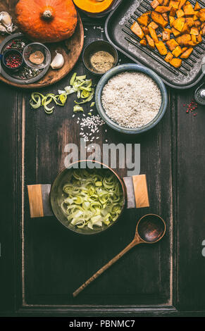 Bestandteile von leckeren Kürbis Teller mit Reis im Topf kocht auf dunklen rustikalen Küche Tisch Hintergrund, Ansicht von oben. Kürbis risotto Vorbereitung. Herbst s Stockfoto