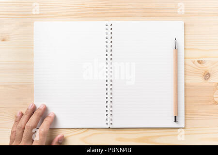 Designkonzept - Ansicht von oben schwarz Kraftpapier Spirale notebook, Hand des Menschen und Holz Bleistift auf Holz Tisch Hintergrund für mockup Stockfoto