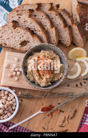 Hummus mit Vollkorn Sauerteigbrot, Paprika und Zitrone Stockfoto