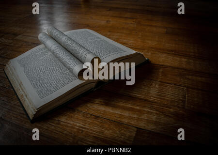 Buch auf einem Holzboden mit heartshaped Seiten in der Mitte und ein wenig natürliches Licht zu öffnen. Stockfoto