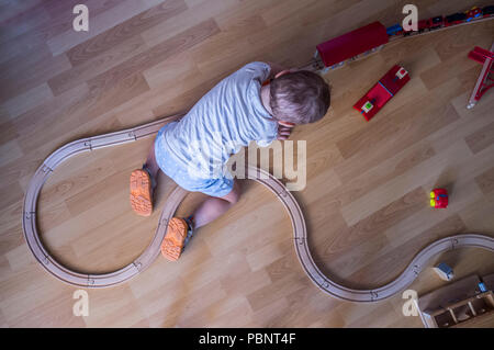 Kind Junge spielt mit hölzernen Spielzeugeisenbahn. Ansicht von oben. Pädagogische Spielwaren Stockfoto