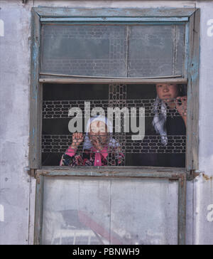 Mädchen und Mama im Fenster, Sary Mogul Basar, Kirgisistan Stockfoto