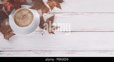 Heißer Kaffee Cappucino und Herbstlaub auf alten weißen Holz- Hintergrund. Saisonale Konzept entspannen, flach Stockfoto