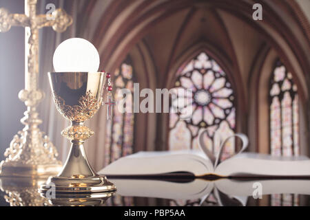 Römisch-katholische Kirche. Das Kreuz, Bibel, Rosenkranz und goldenen Kelch auf dem Altar. Stockfoto