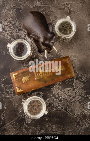 Verschiedene Arten von Tee in Gläsern, Holzbox mit Tee und Figur aus Holz Elefant Stockfoto