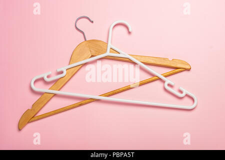 Holz- und Kunststoff Kleiderbügel isoliert und werfen Schatten auf rosa Hintergrund Stockfoto