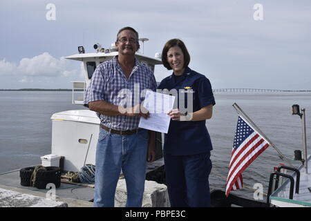 Kapitän Megan Dean, der Kommandant der Küstenwache Sektor Miami ein Zertifikat der Inspektion Kapitän Mike Rivera, Kapitän der tugboat Peggy Ann, in den Hafen von Miami, 20. Juli 2018. Die Zertifikate der Inspektion auf den Schlepper Peggy Ann, Jean Ruth und Miami ausgestellt sind das Ergebnis von Jahren der Arbeit zwischen Ihnen und der Küstenwache zu schaffen Sicherheit Vorschriften für die Inspektion Normen und Safety Management Systems von Abschleppen von Schiffen. Coast Guard Foto von Petty Officer 3. Klasse Brandon Murray. Stockfoto