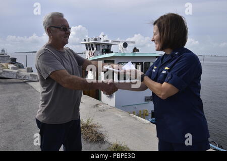 Kapitän Megan Dean, der Kommandant der Küstenwache Sektor Miami, ein Zertifikat der Inspektion Kapitän Norman Hempstead, Kapitän der tugboat Jean Ruth, 20. Juli 2018. Die Zertifikate der Inspektion auf den Schlepper Peggy Ann, Jean Ruth und Miami ausgestellt sind das Ergebnis von Jahren der Arbeit zwischen Ihnen und der Küstenwache zu schaffen Sicherheit Vorschriften für die Inspektion Normen und Safety Management Systems von Abschleppen von Schiffen. Coast Guard Foto von Petty Officer 3. Klasse Brandon Murray. Stockfoto