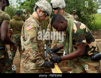 Soldaten mit der North Dakota National Guard und der Ghana Streitkräfte Messen und Schneiden Bauholz Strukturen an der Bundase Training Centre in Ghana Juli 20, 2018 als Teil der United Accord 2018 montieren. UA 18 ist ein Ghana Bundeswehr & U.S. Army Afrika hosted Übung bestehend aus vier kombinierten, gemeinsame Komponenten: einen Computer programmiert Übung (CPX), Field Training übung (Ftx), Jungle Warfare School (JWS) und medical Readiness Training (MEDRETE). Westafrikanischen partner Militärs, Verbündeten in der NATO und der US-Armee Afrika wird jede Komponente in Accra, Ghana und Umgebung. (U.s. Stockfoto