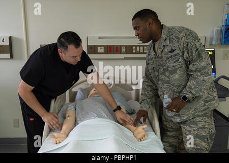 Dominic Trujillo-Hobbs, 374 medizinische Gruppe simulation Operator, zeigt Oberst Otis C. Jones, 374 Airlift Wing Commander, Puls Punkte auf der SimMan 3G Training Werkzeug während der 374 MDG immersion Tour an Yokota Air Base, Japan, 24. Juli 2018. Die Simulation Lab Züge mehr als 800 Studenten, Anhäufung von 1.800 Stunden Training auf einer jährlichen Grundlage, das Personal auf dem neuesten Stand über Ihre lebensrettenden Zertifizierungen. (U.S. Air Force Foto von Airman 1st Class Matthew Gilmore) Stockfoto